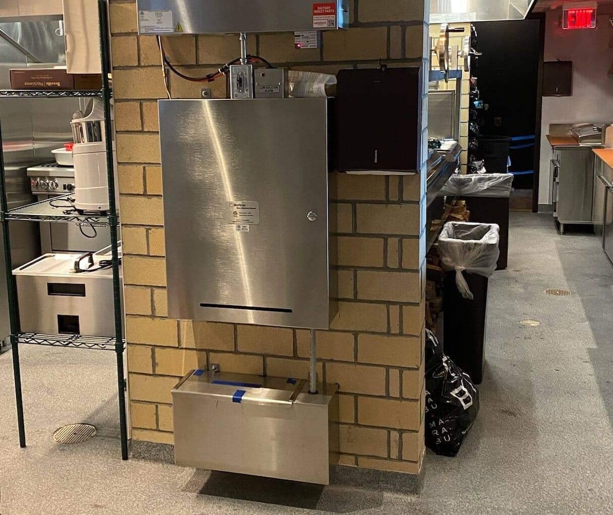 MOAS cabinet on a tiled kitchen wall with its solution container at floor level.