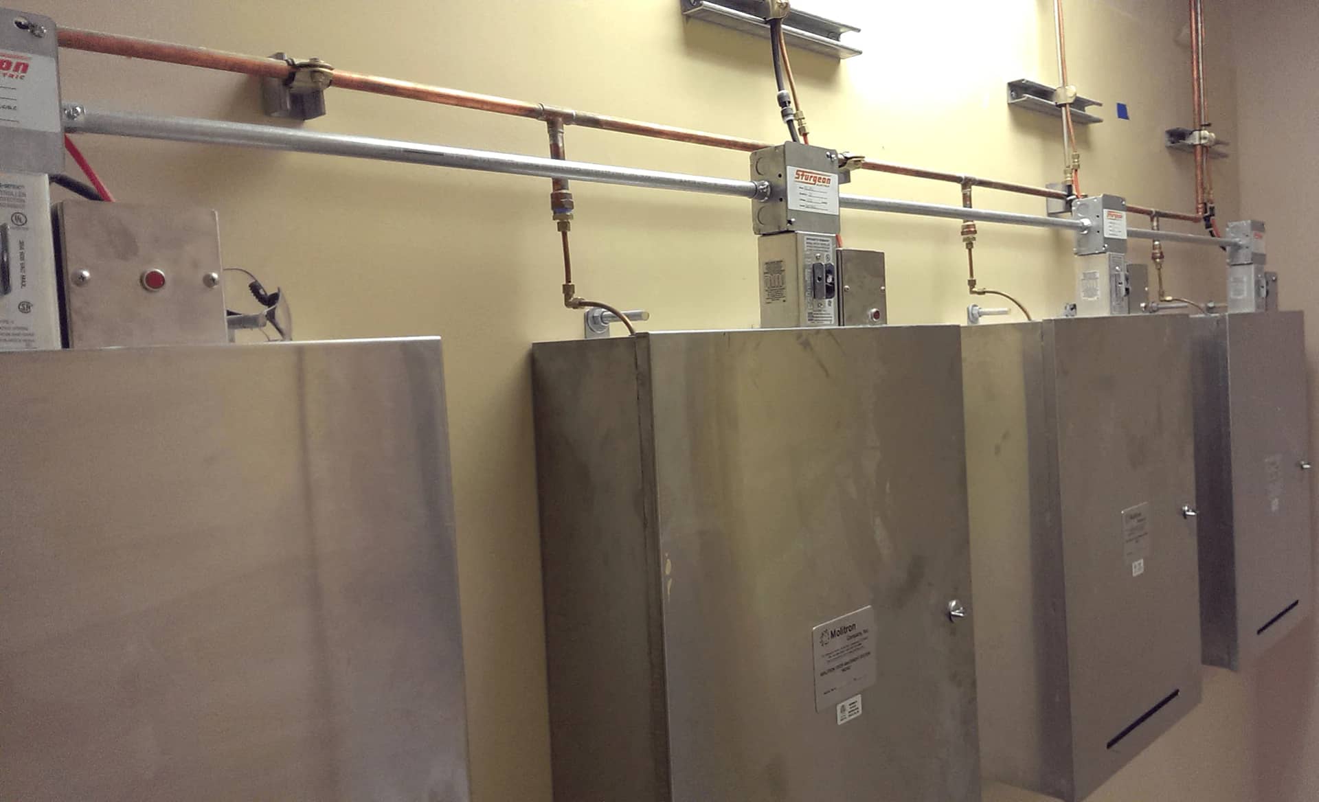 Four MOAS cabinets mounted side by side beneath their supply piping.